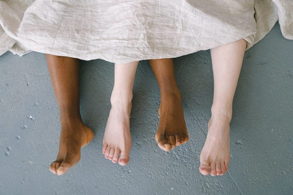 Three Pairs of Bare Feet, Varying Skin Tones, Under a Blanket — Tewantin Medical Centre In Tewantin, QLD