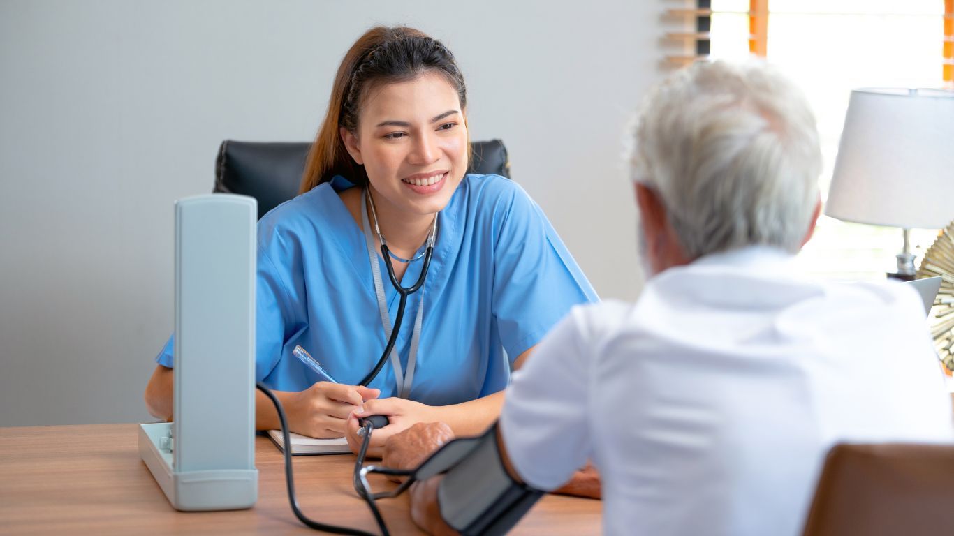 A Healthcare Professional is Smiling While Speaking With an Older Male Patient — Tewantin Medical Centre In Tewantin, QLD