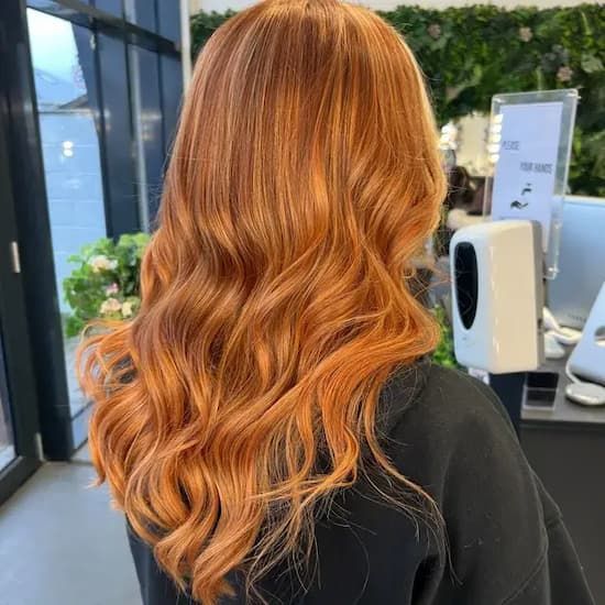 Woman with long, wavy, orange hair in a salon, wearing a black shirt — Tewantin Medical Centre In Tewantin, QLD