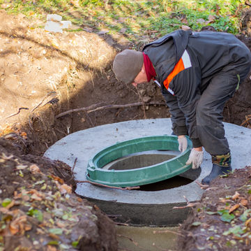 A man is working on a manhole cover in the dirt.