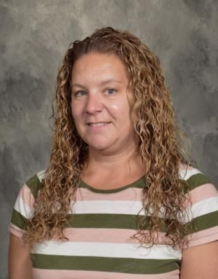 a woman with curly hair is wearing a striped shirt and smiling for the camera .