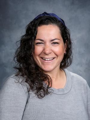 a woman with curly hair is smiling and wearing a headband .