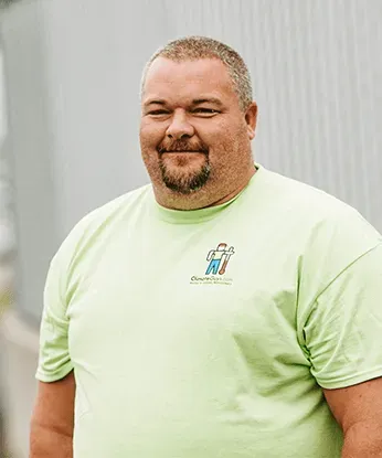 Smiling man in a light green T-shirt standing against a gray background