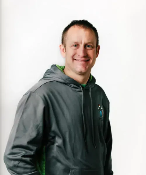 Smiling person in a gray hoodie against a plain light background