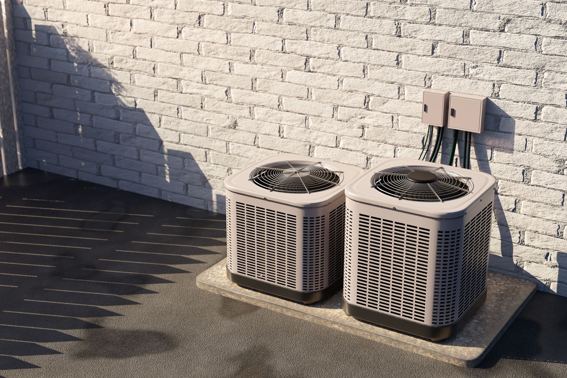 Two beige outdoor air conditioning units beside a brick wall on a sunny patio.