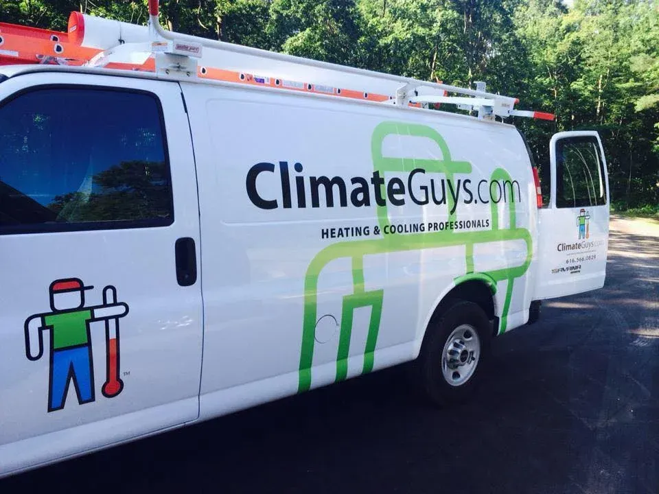 ClimateGuys.com service van parked outdoors, white with green and black logo and technician graphic.