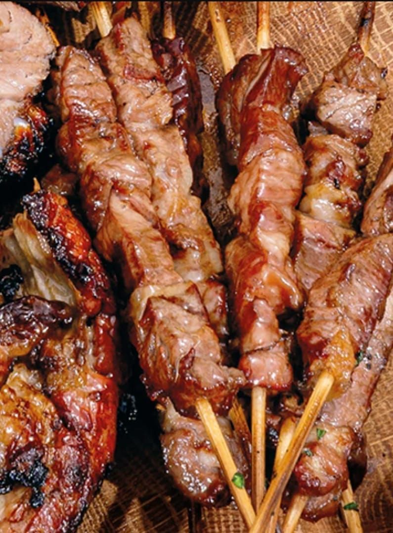 Spiedini di carne alla griglia infilzati su bastoncini di legno.