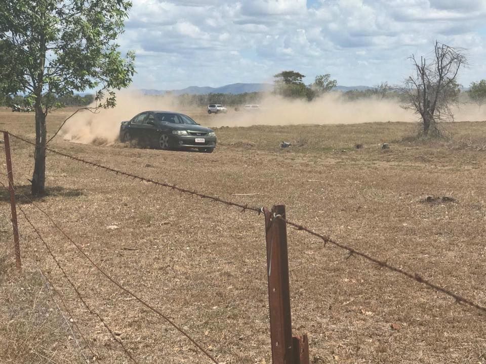 A car is driving through a dirt field next to a barbed wire fence — Zilzie Workshop In Emu Park, QLD
