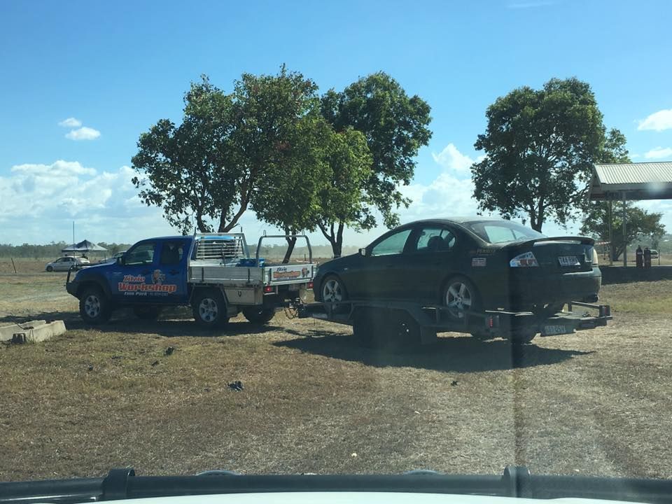 A Blue Truck is Towing a Black Car on a Trailer — Zilzie Workshop In Emu Park, QLD