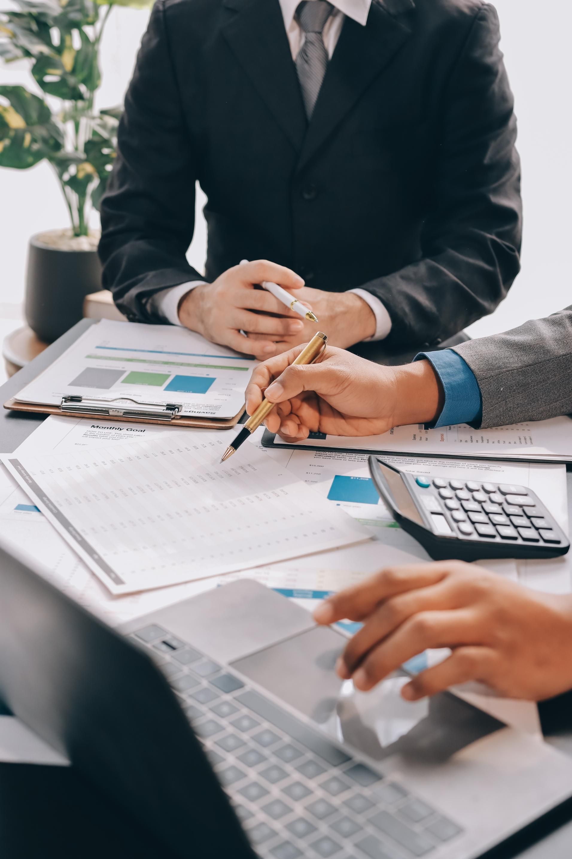 Business team reviewing documents and charts at a desk with laptop and calculator