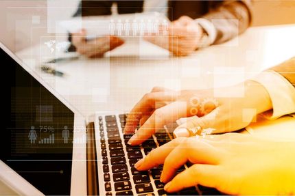Hands typing on a laptop keyboard with a warm orange overlay on the screen and desk.