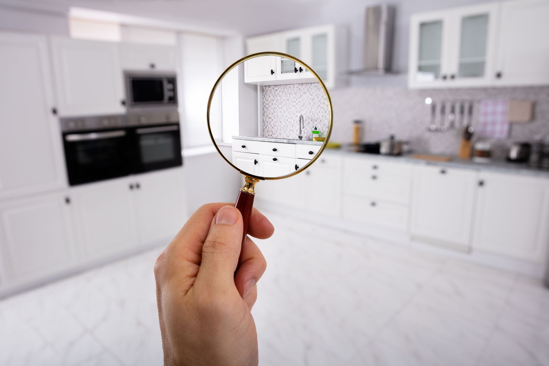 close-up of a man's hand holding magnifying glass over the kitchen