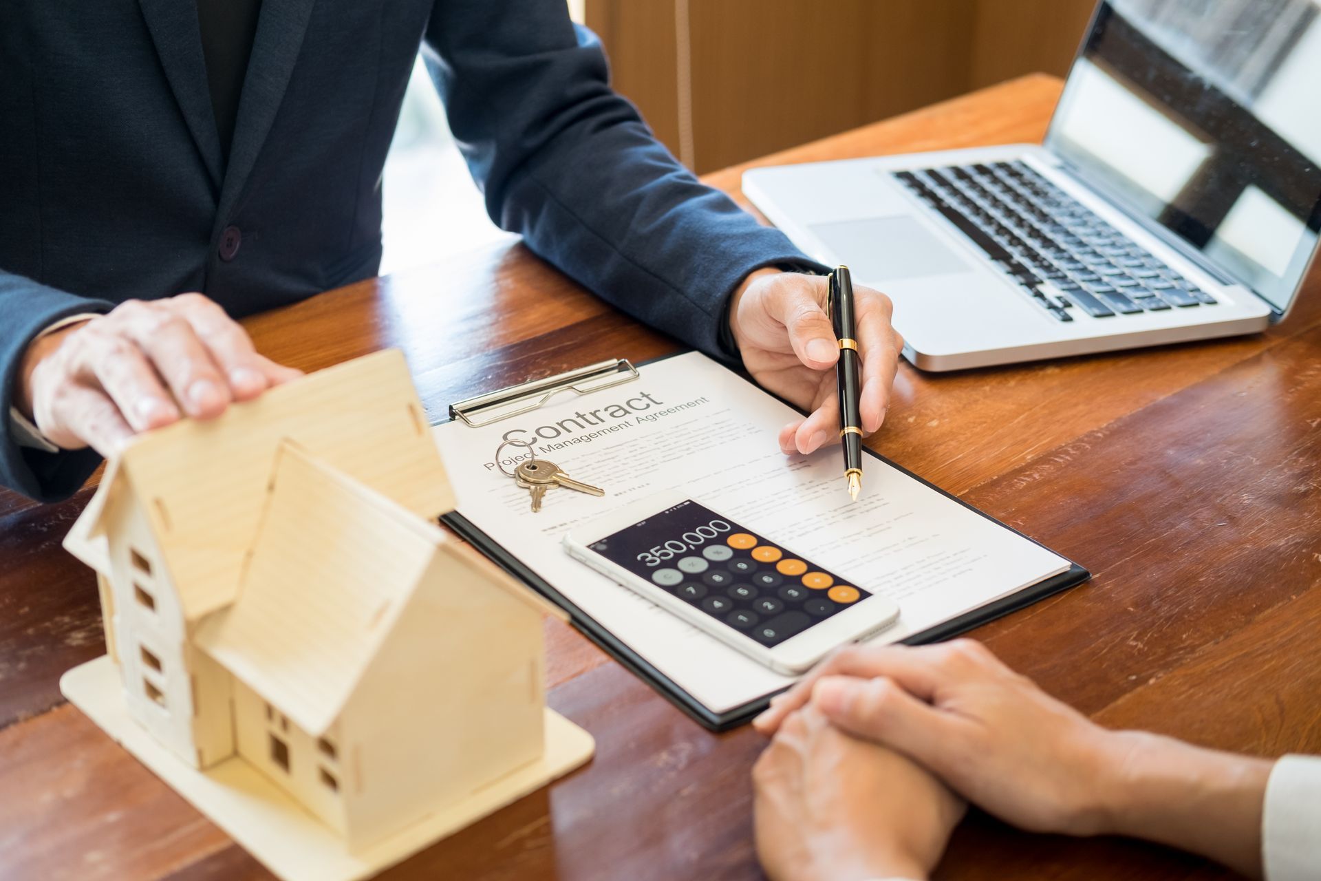 businessman signs contract behind home architectural model discussion with a real estate agent
