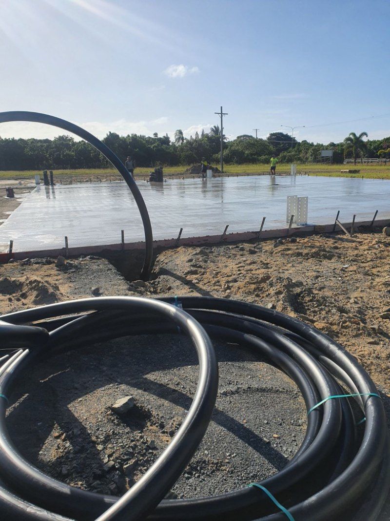 A Hose Is Laying On The Ground In Front Of A Concrete Slab — Bark Concreting In Ryan, QLD