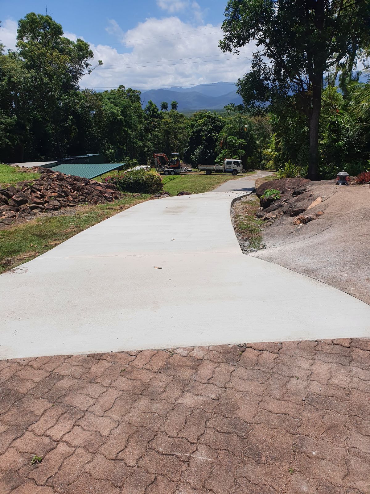 A Concrete Driveway Leading to a House With Trees on Both Sides — Bark Concreting In Ryan, QLD