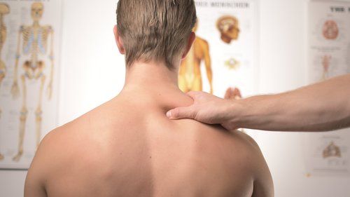 A man is getting a massage on his back in front of a skeleton.