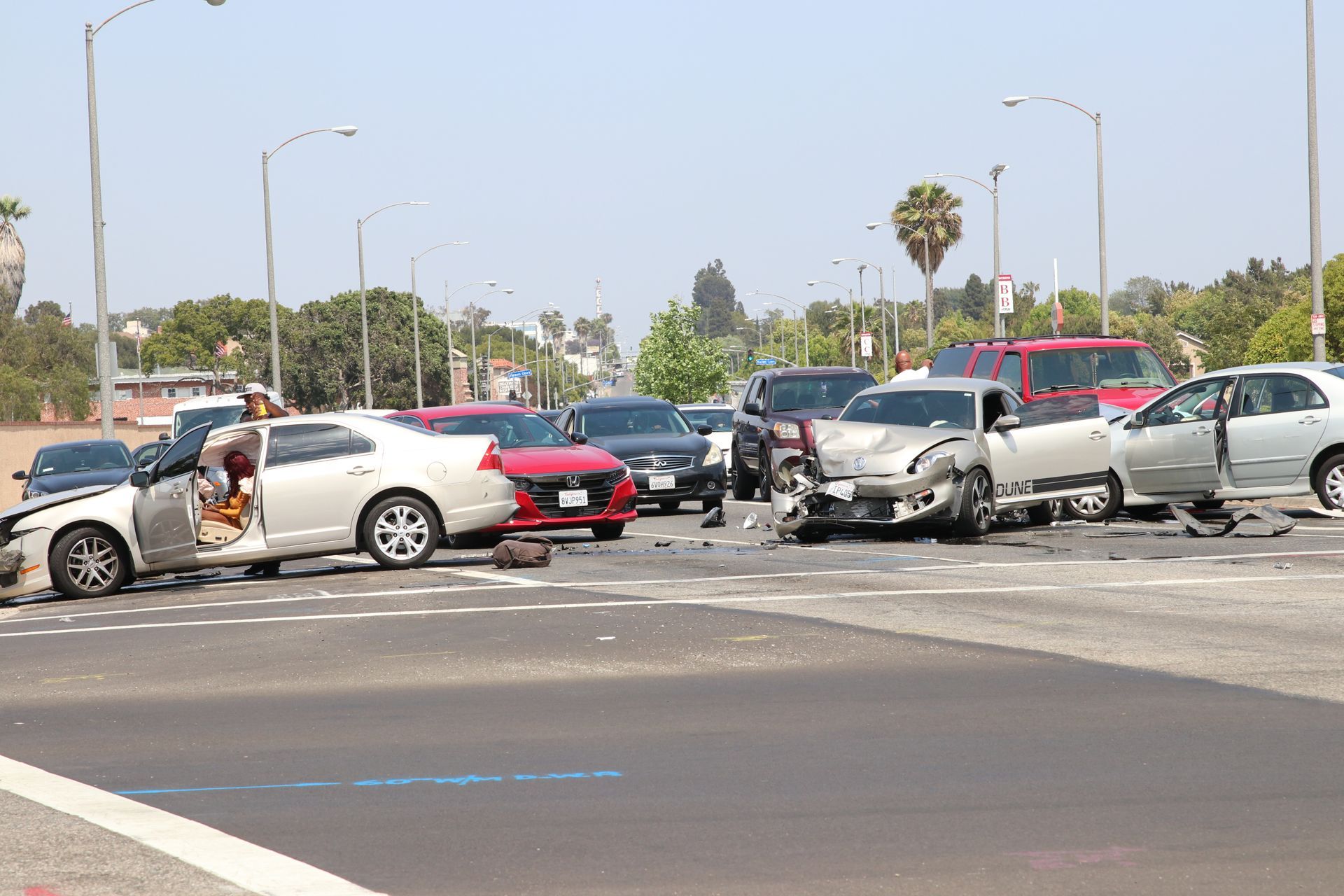 Damaged cars and debris block a street after a multi-car crash under a clear sky