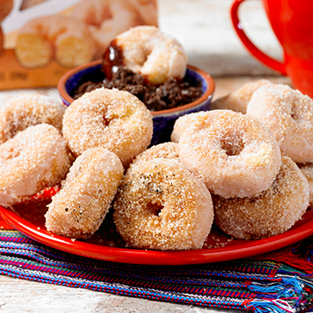 glazed mini donuts churro style with chocolate dipping sauce on red plate