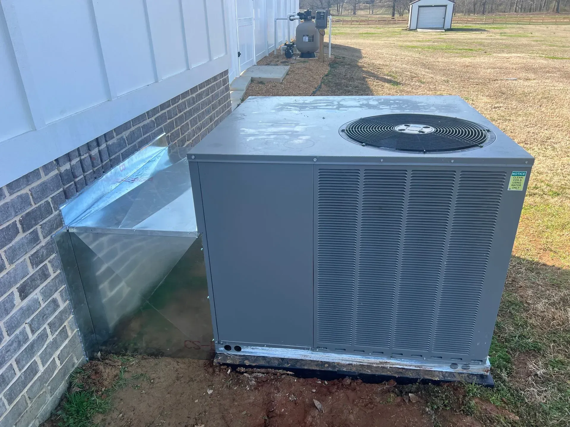 A large air conditioner is sitting on the side of a brick building.