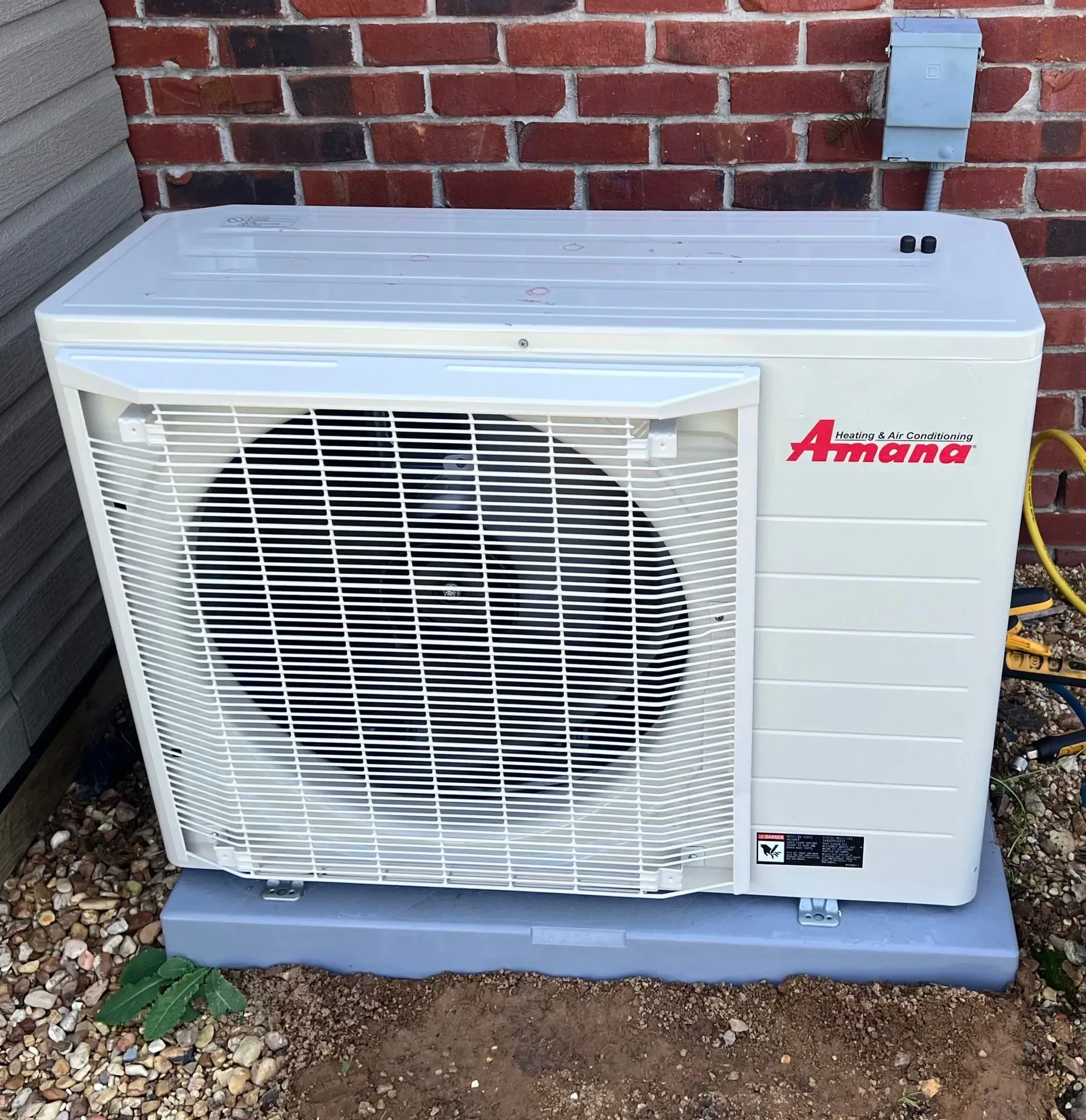An amana air conditioner is sitting outside of a brick building