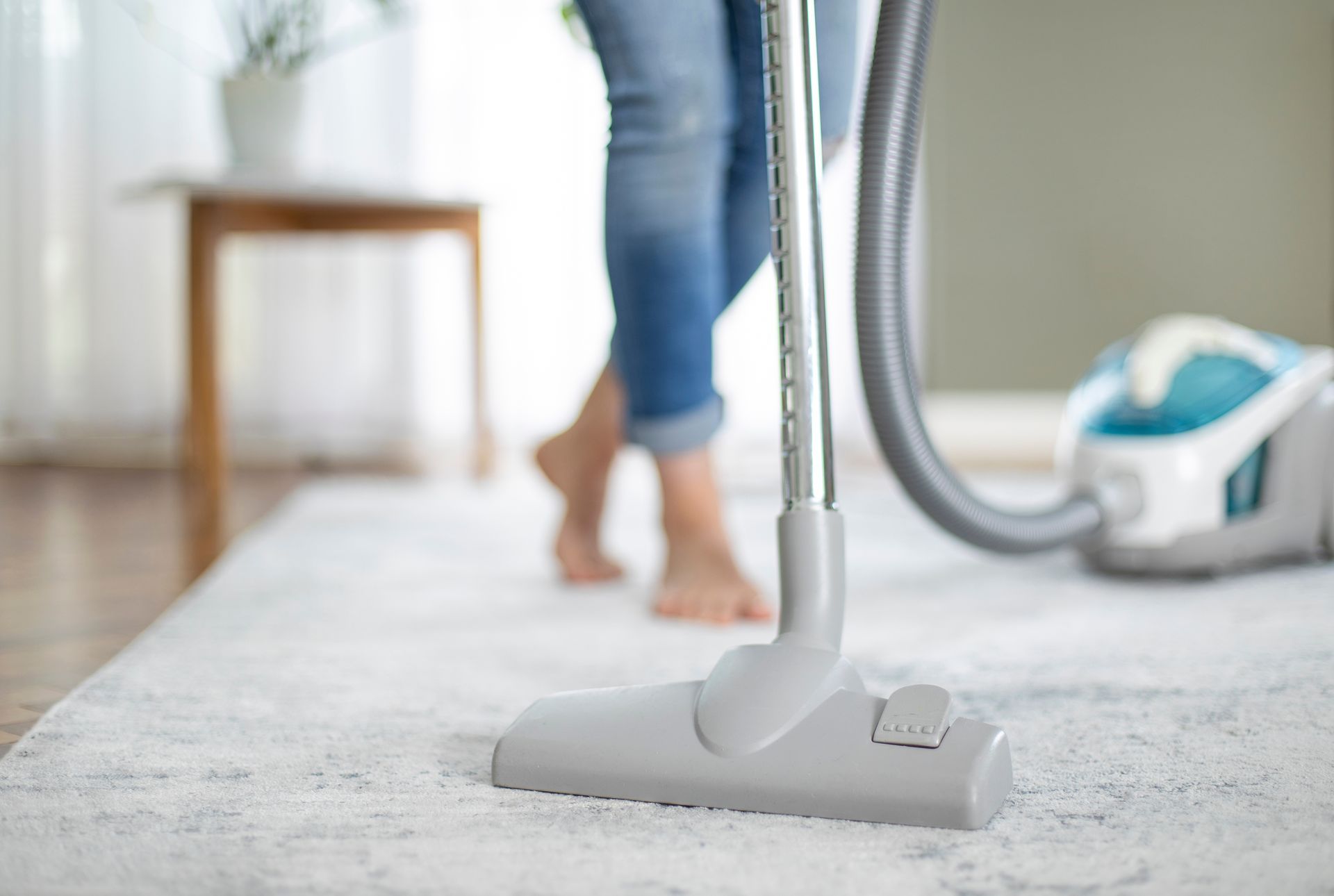 Vacuum cleaner on a rug with a person walking barefoot in the background