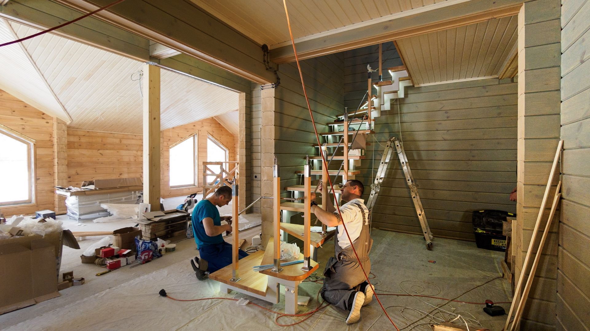 Two workers installing a staircase in an unfinished house interior