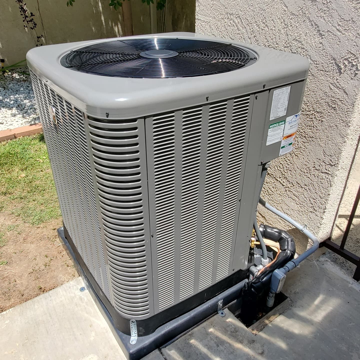 Outdoor HVAC service scene with a gray condenser unit, gauges, and tools on the ground