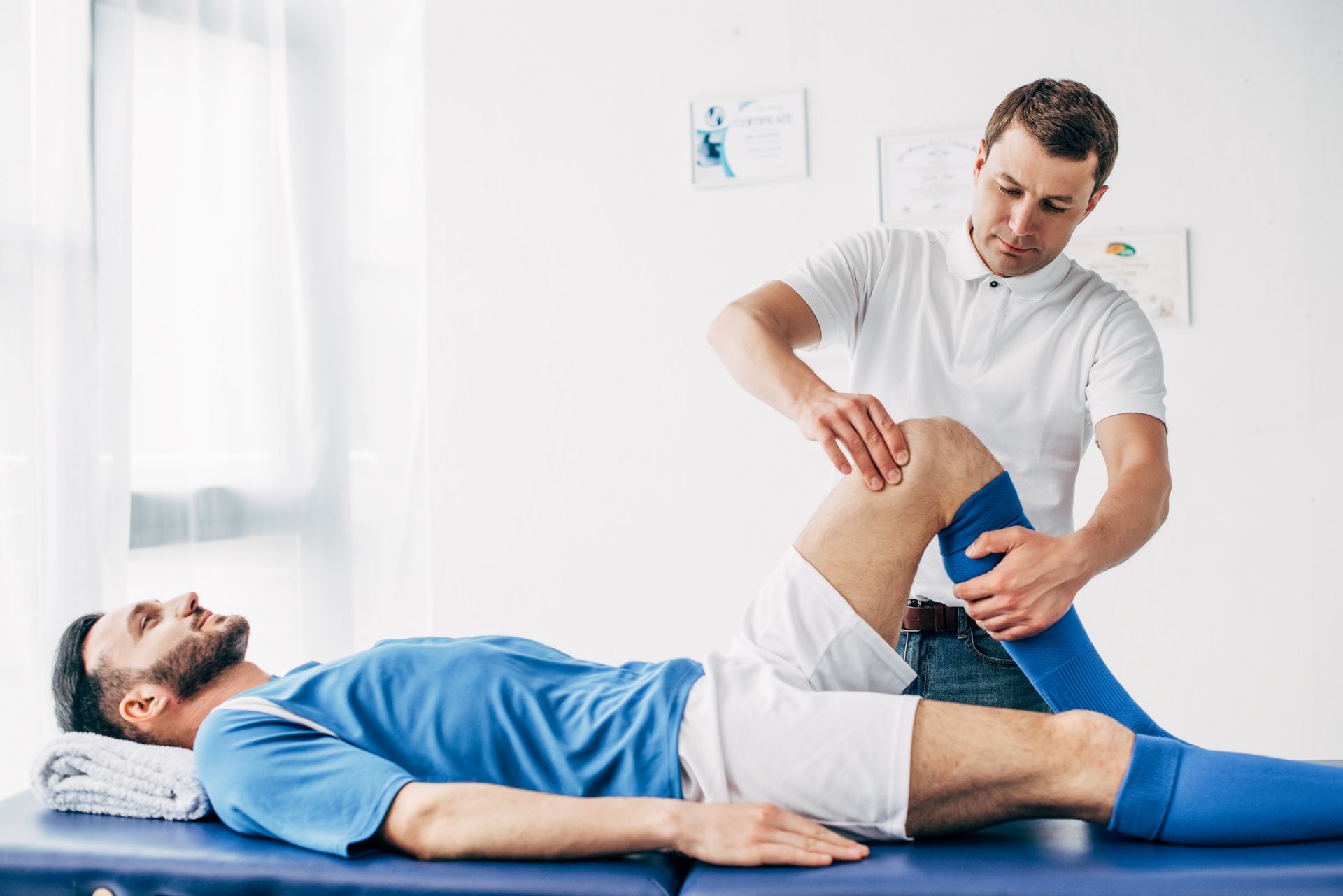 A physiotherapist massaging the leg of football player.