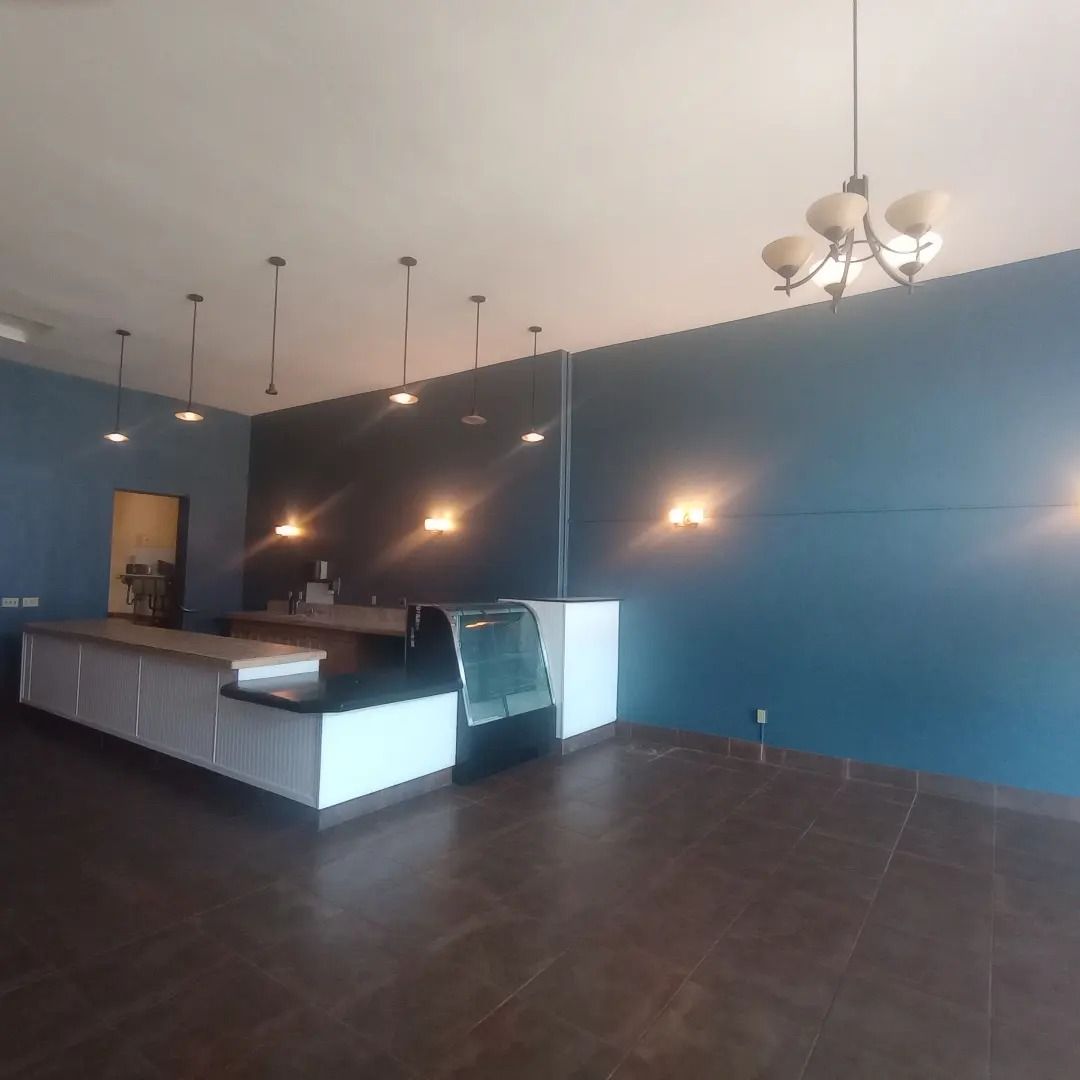 Empty modern kitchen and dining area with blue walls, dark tile floor, and pendant lights