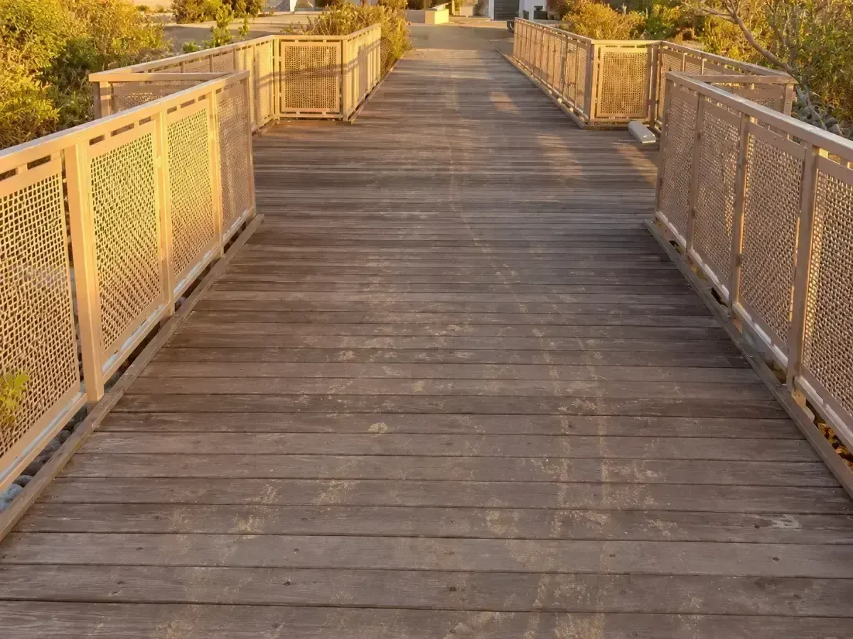 Wooden boardwalk with ornate railings leading into the distance at sunset