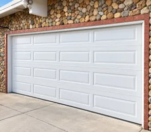White double garage door on a stone exterior wall with a concrete driveway.