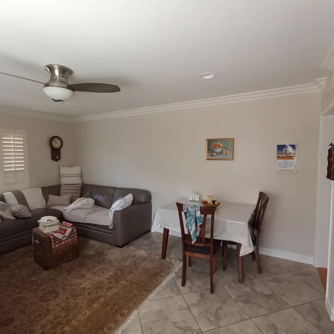 Living room with gray sectional, dining table, ceiling fan, and tiled floor