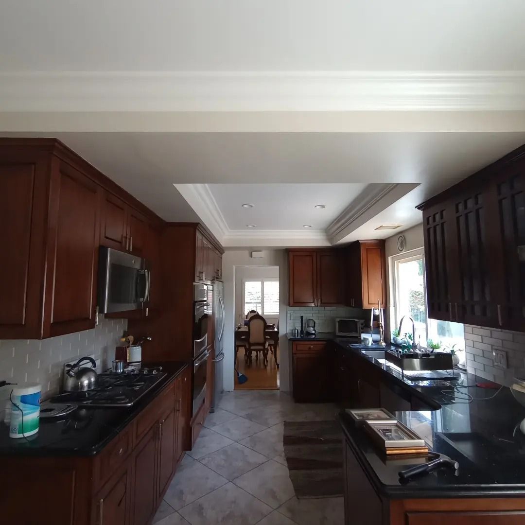 Kitchen with dark wood cabinets, black countertops, tiled floor, and a dining area in the background
