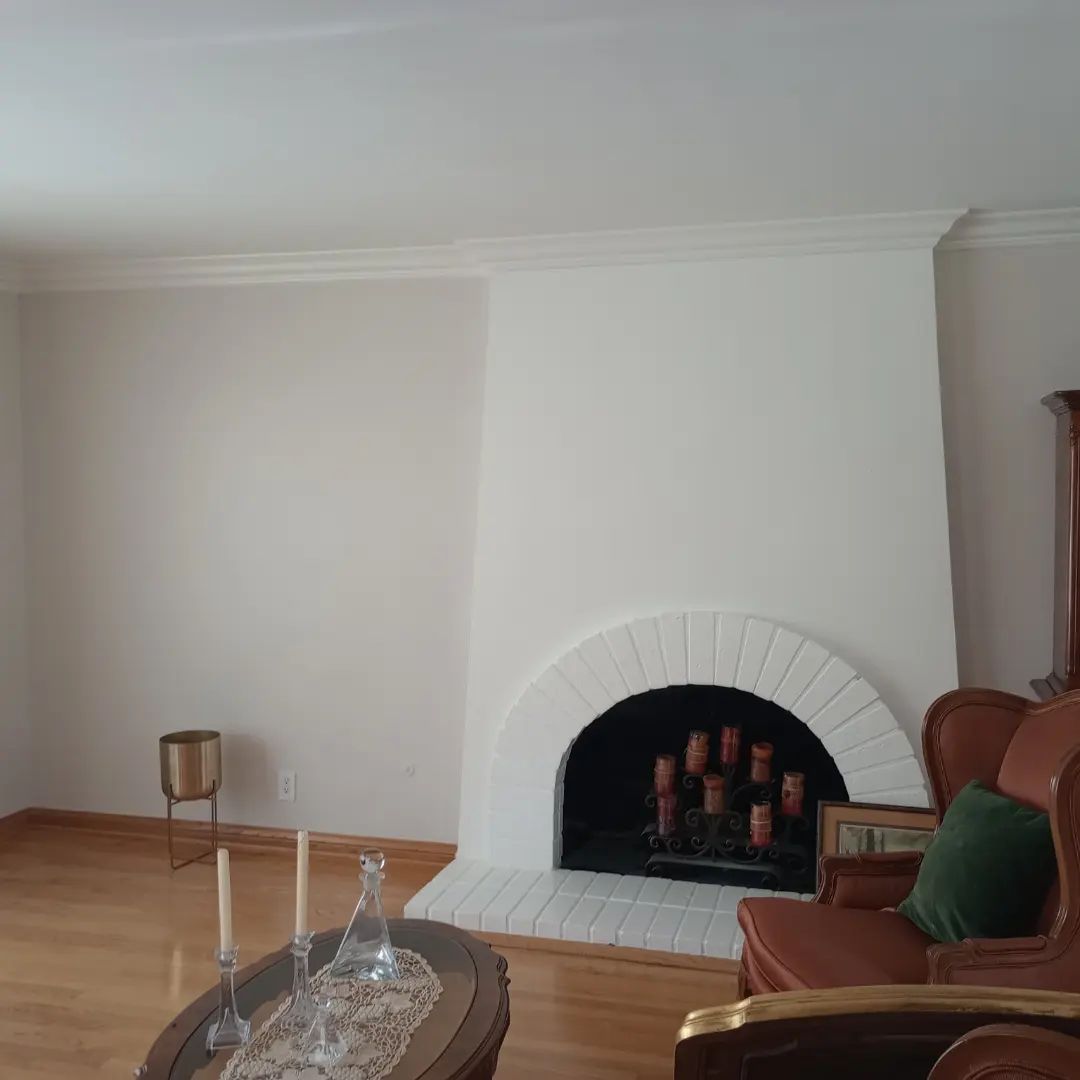 Minimal living room with white walls, arched fireplace, brown chair, and glass coffee table