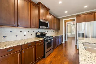 Modern kitchen with wood cabinets, stainless steel appliances, granite counters, and hardwood floors