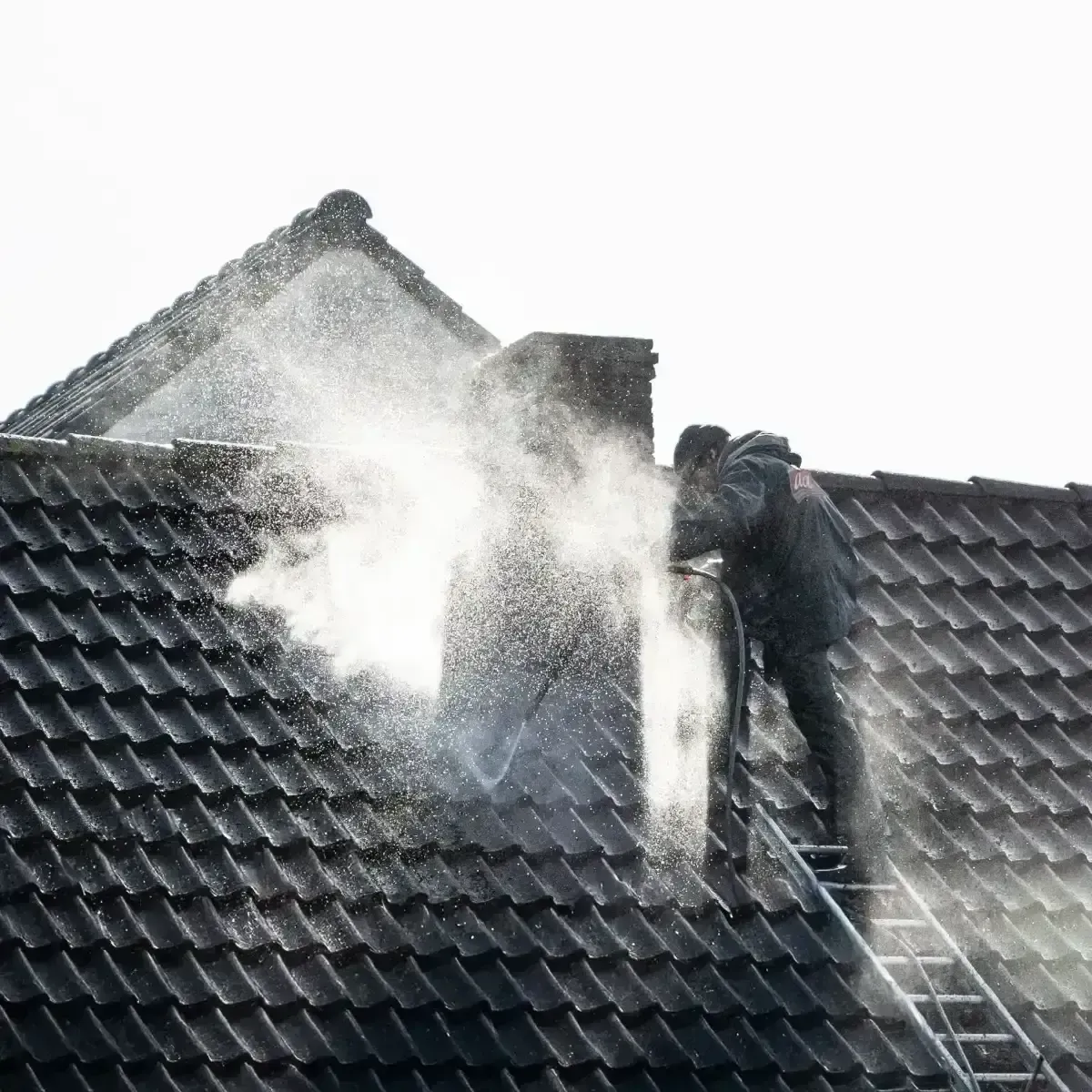 Firefighters spraying water on a house roof with heavy smoke or steam rising