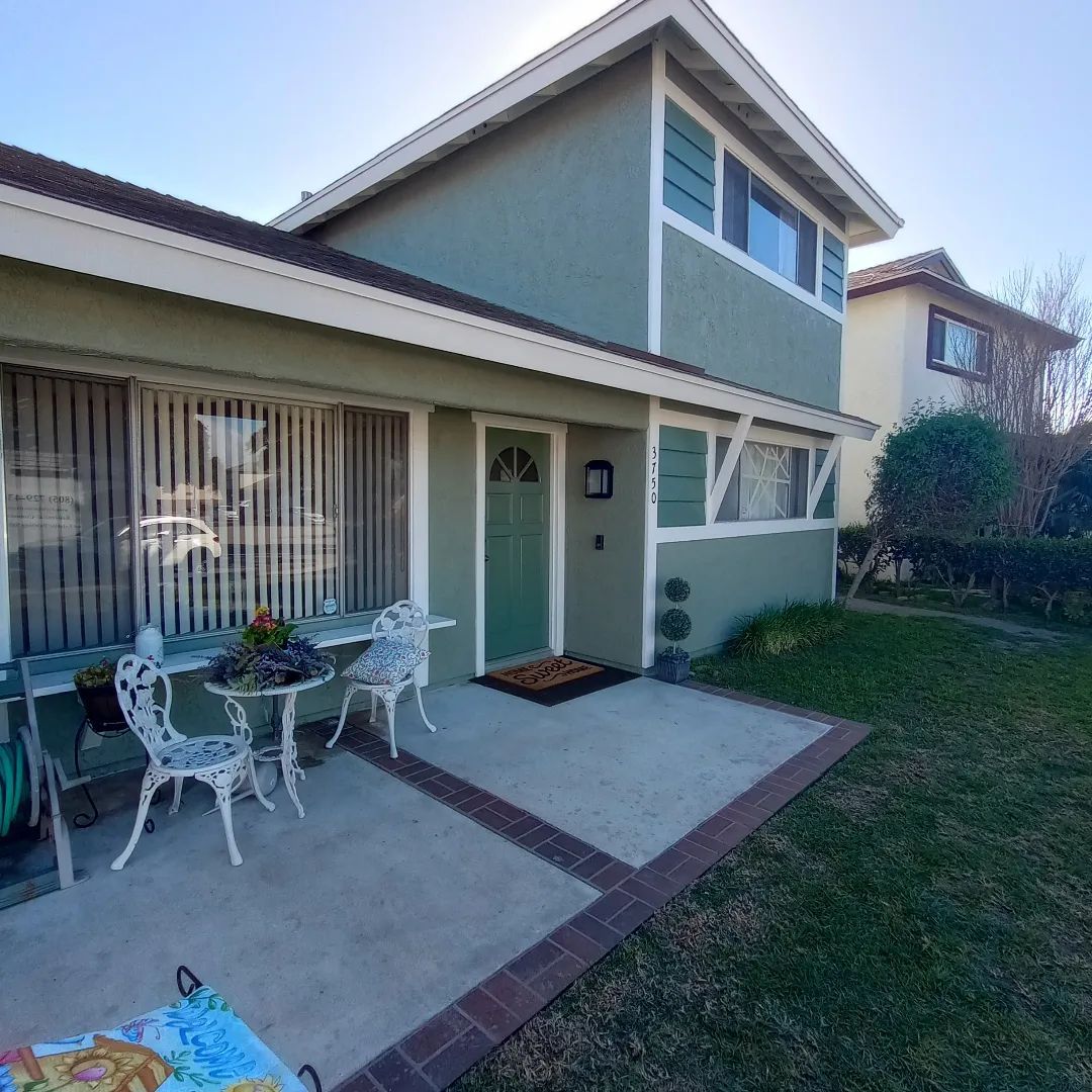 Small house patio with white table and chairs, sliding glass door, and a grassy yard.
