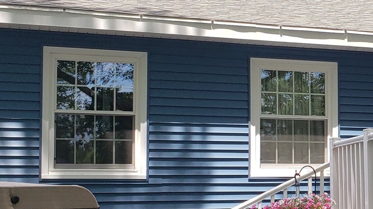 A blue house with white trim and two windows