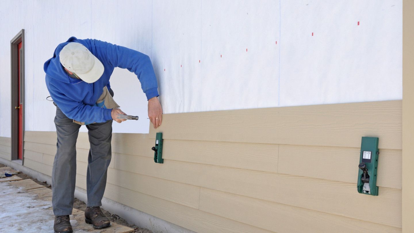 A man is hammering a nail into a wall .
