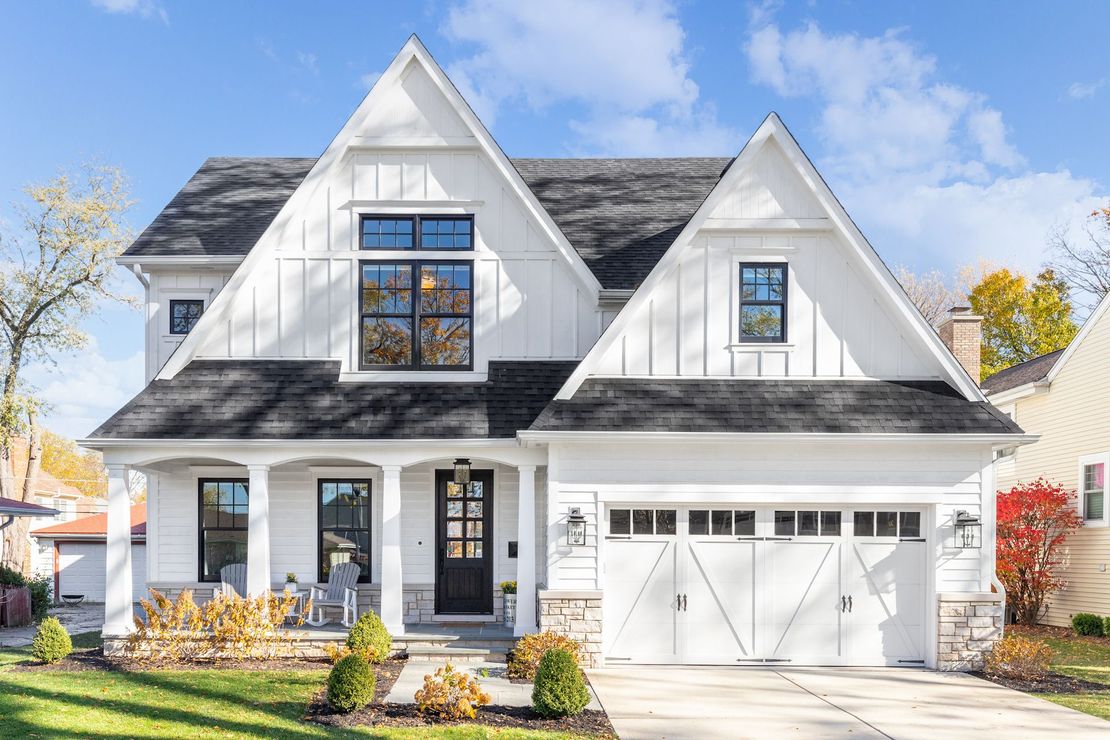 A white house with a black roof and a black garage door