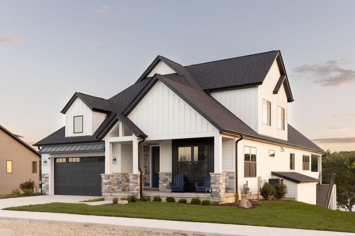A white house with a black roof and a black garage door