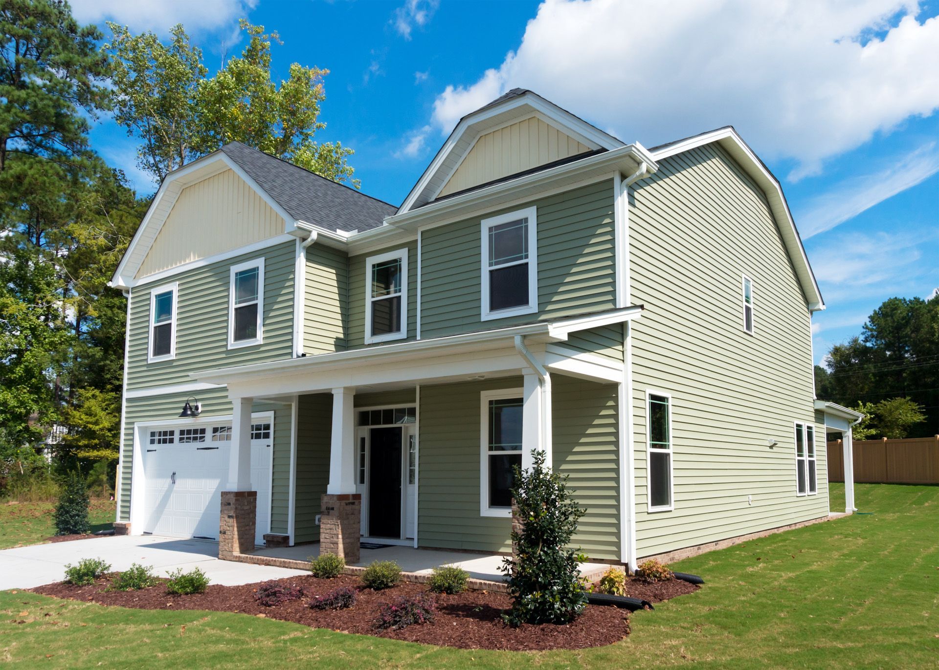 A green and white house with a garage and a porch