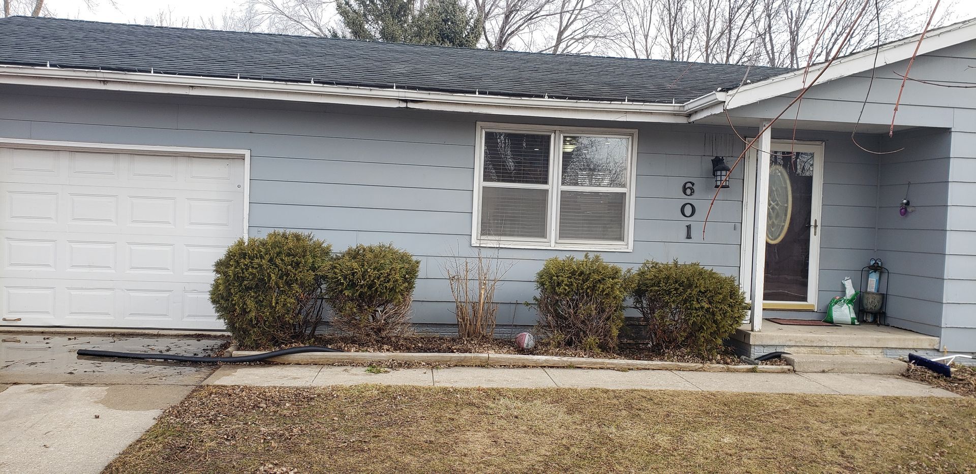 A blue house with a white garage door and a black roof