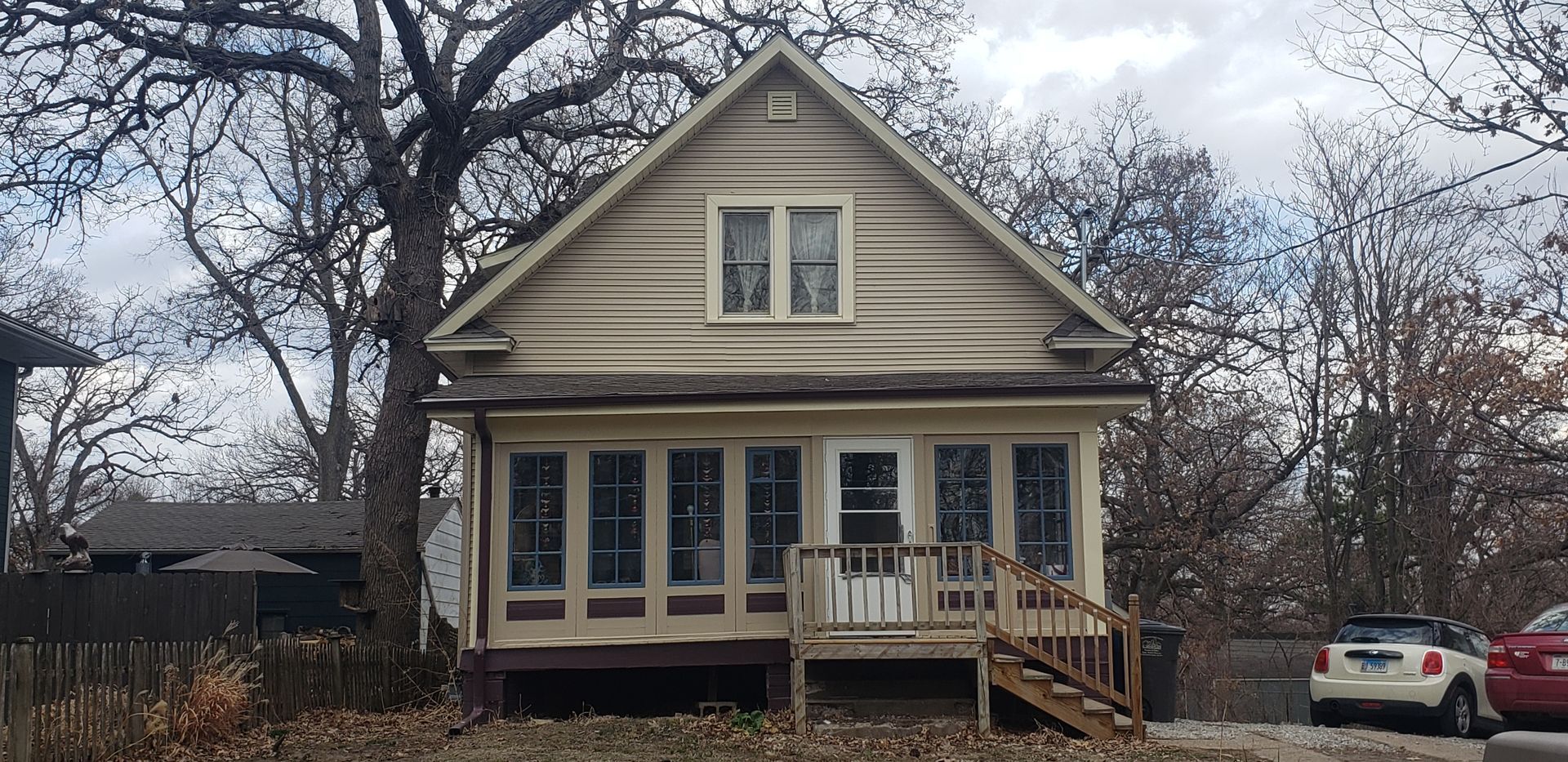 A house with a lot of windows and a red car parked in front of it