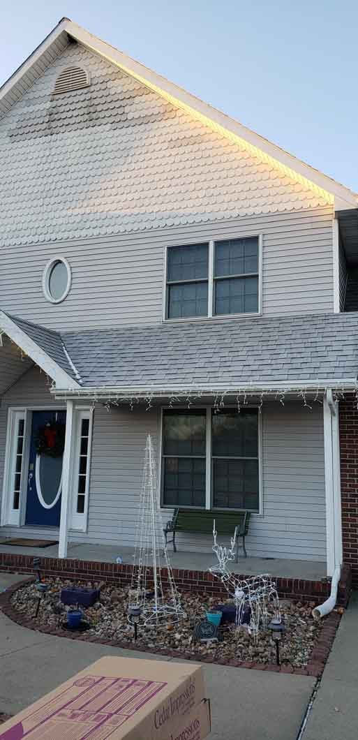 A white house with a porch and a box in front of it