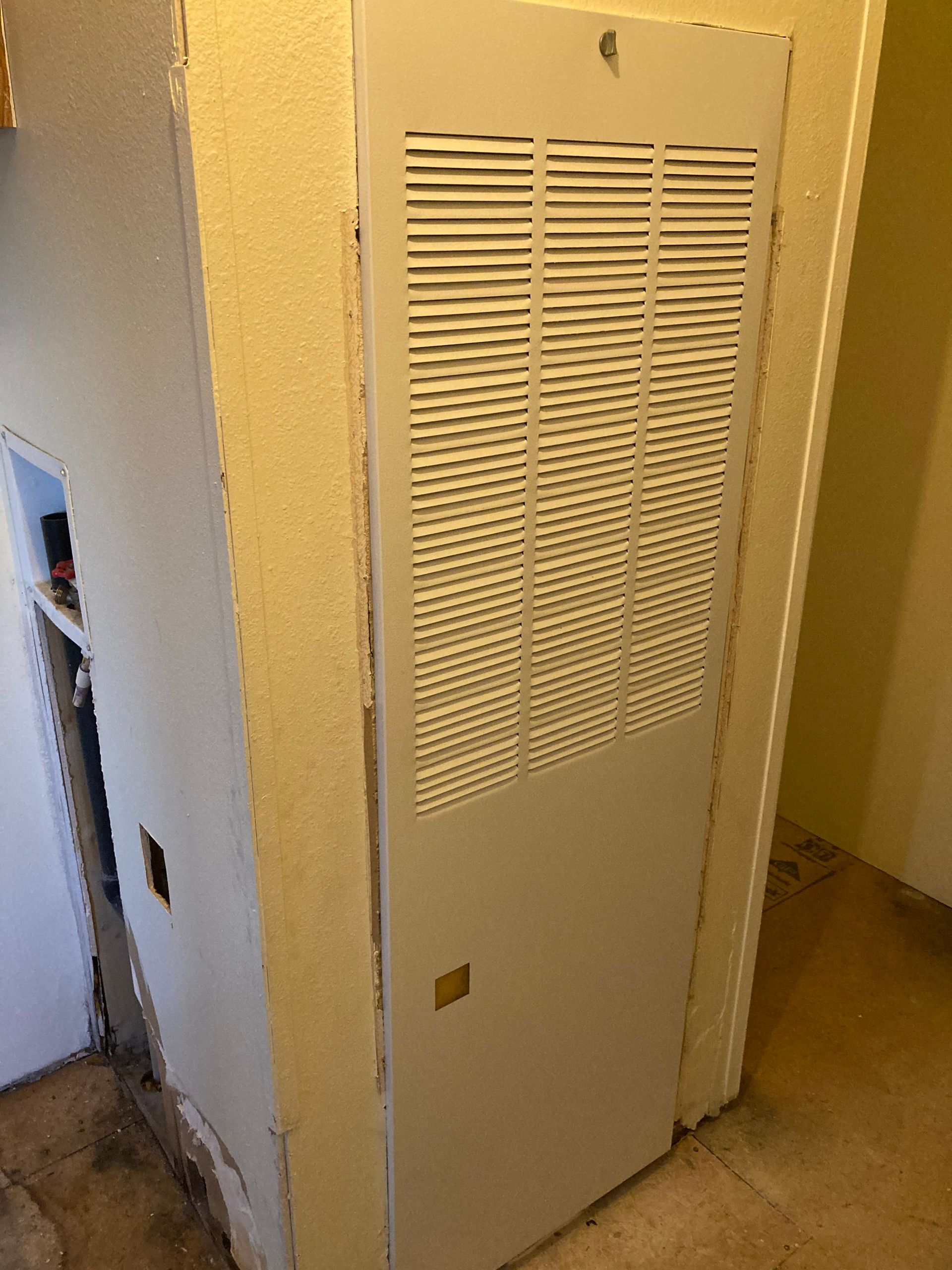 A white door with holes in it is in a room next to a door.
