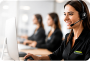 Customer service agent wearing a headset, smiling at a computer in a bright office
