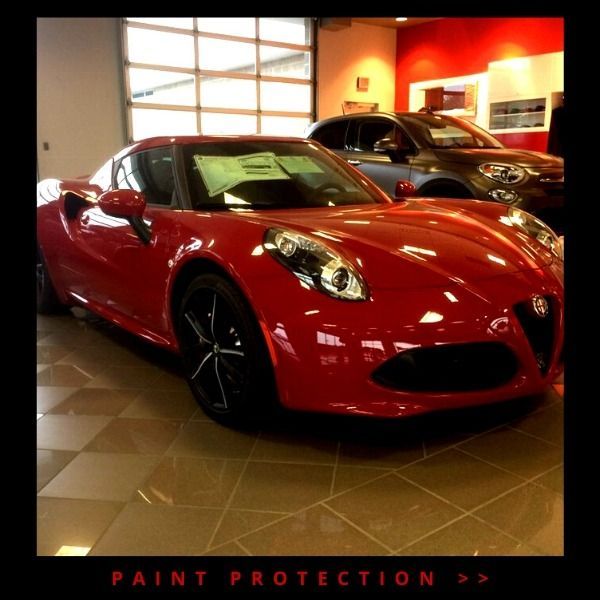 Red sports car in a showroom with “PAINT PROTECTION” text below