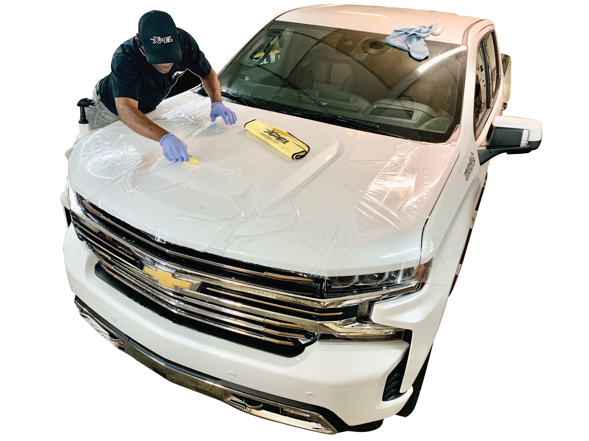 Person cleaning a white Chevrolet SUV hood with a sponge and gloves