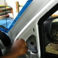 Hand opening a car door near the front pillar, showing the interior and side mirror